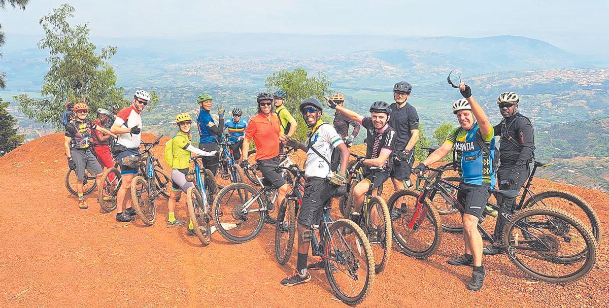 Javier González con camiseta naranha rodeado de otros ciclistas en una montaña de Ruanda.