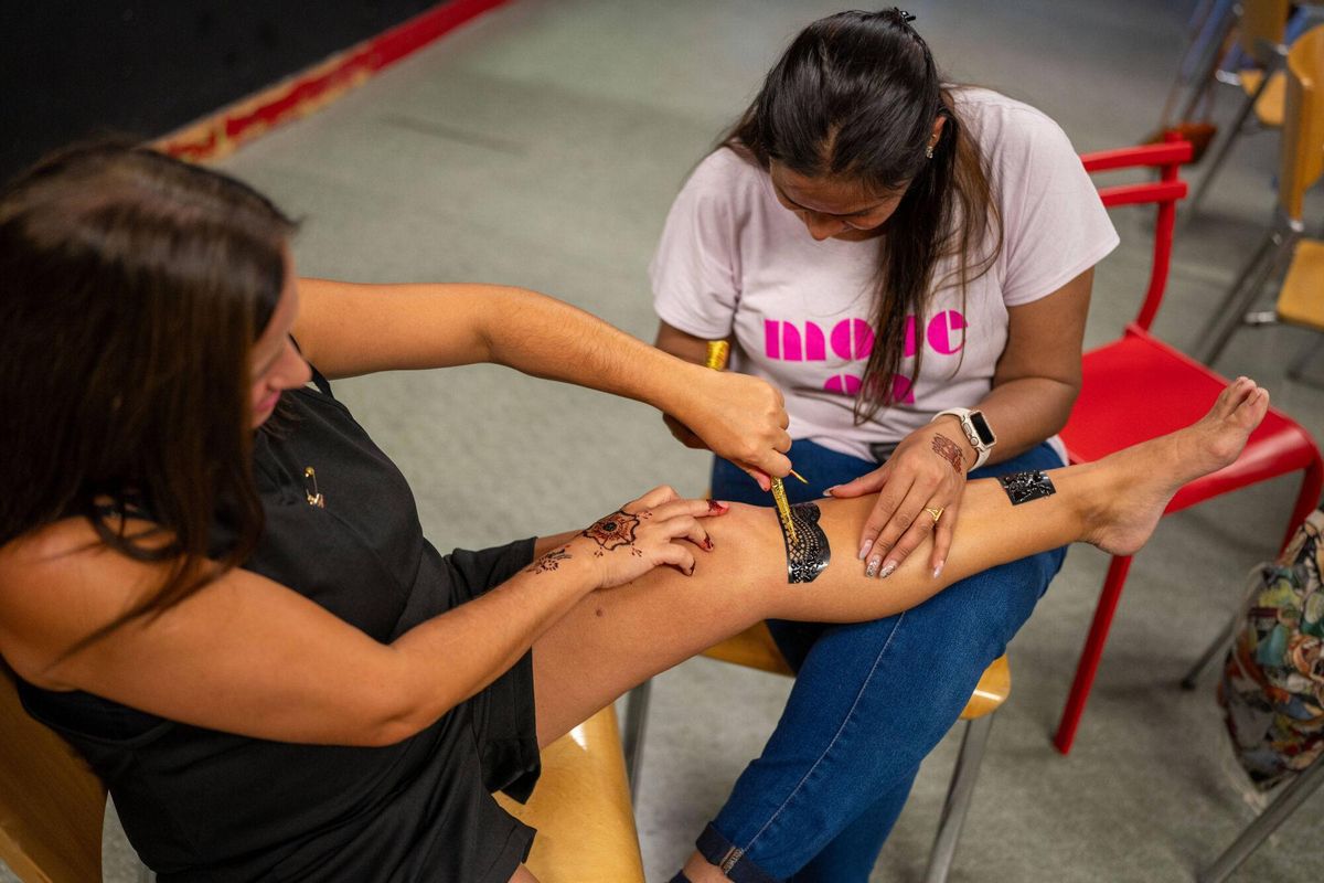 Un grupo de mujeres de entre 20 y 80 años, vecinas del barrio de la Trinitat Vella y usuarias del Centre de Vida Comunitària, participan en un taller de henna dentro de un casal de verano femenino.