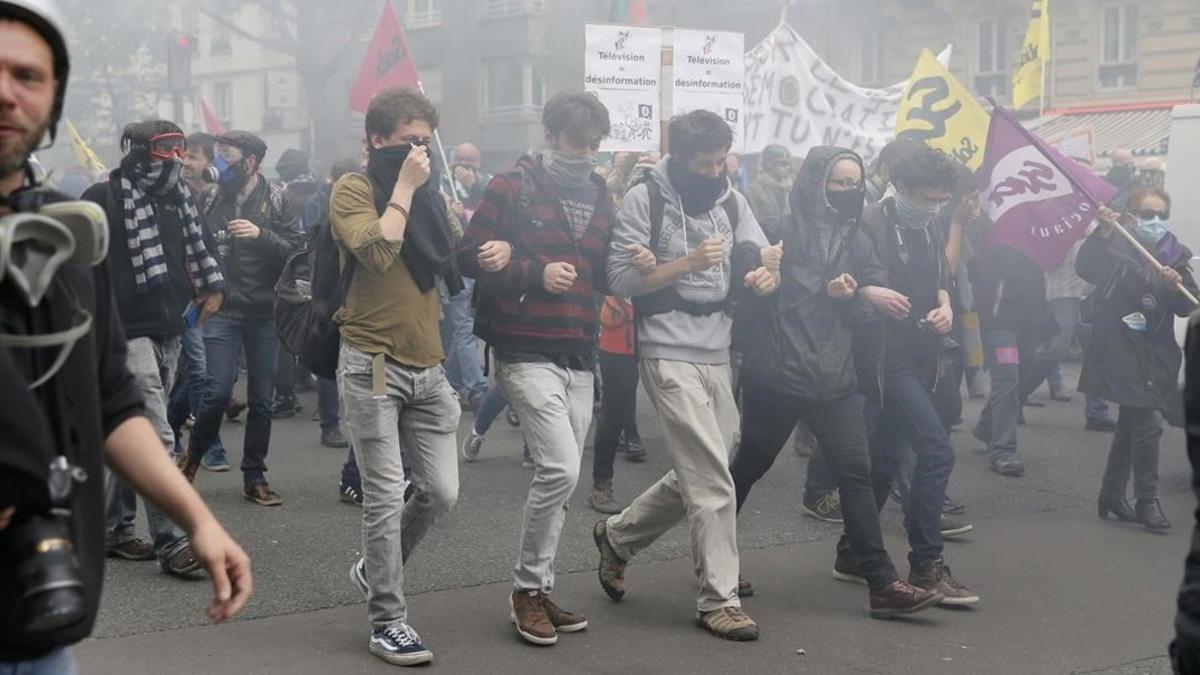 Estudiantes protestan entre gases lacrImógenos de la policía contra la reforma laboral.