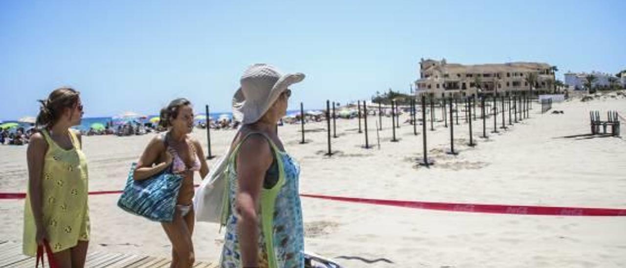 Tres bañistas saliendo este verano de la playa de La Zenia, en Orihuela Costa.