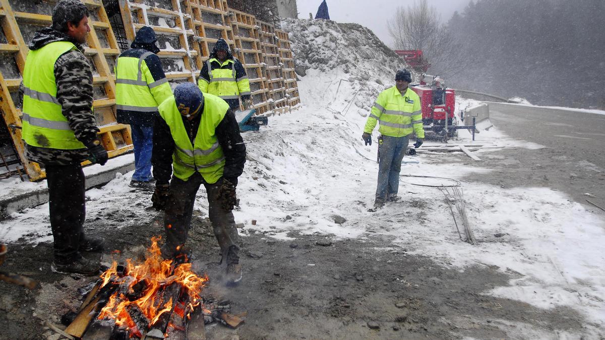 Obreros trabajando con una hoguera en la carretera de la Bonaigua, Lleida, intentando pasar el frio