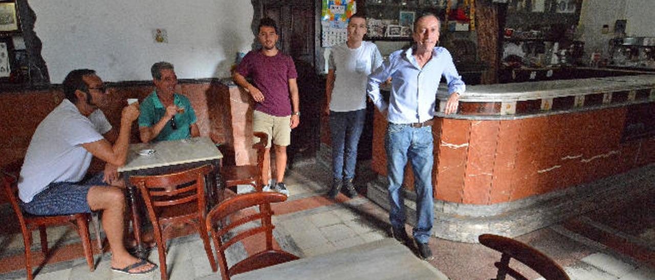 Por la derecha, Ventura, Mario y Ronald Ramírez, en el bar ayer, antes de cerrar, con dos de sus clientes mientras toman su último café en el local.