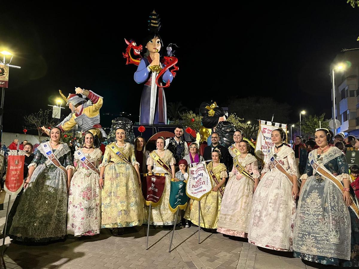 Integrantes de la comisión de Ja Estem Tots, con los banderines logrados, delante de su monumento fallero.