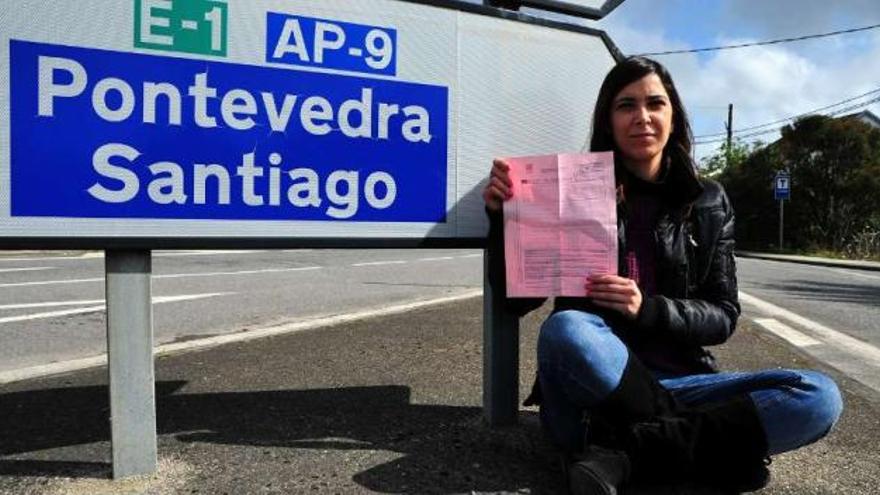 Amara Ínsua Lema, con su reclamación, ante un cartel de la Autopista do Atlántico.  // Iñaki Abella