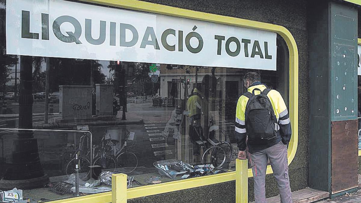 Un ciudadano mira el escaparate de una tienda en liquidación.