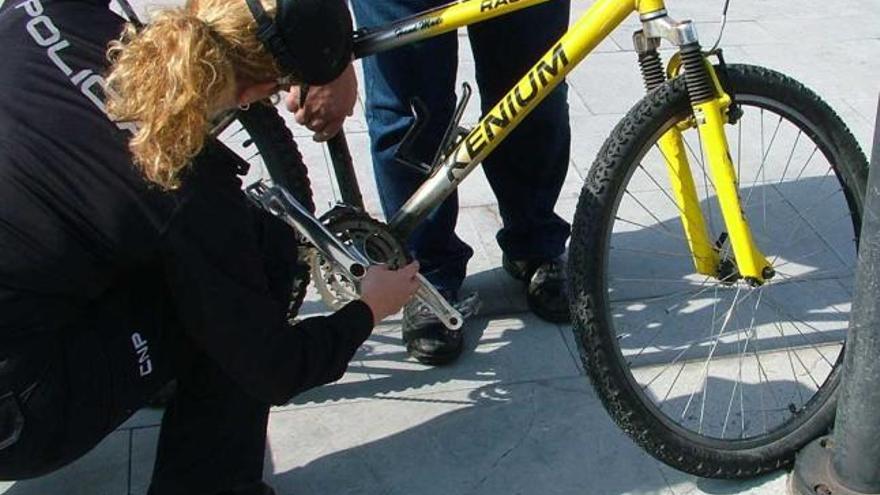 Una agente comprueba el número de serie de una bicicleta.