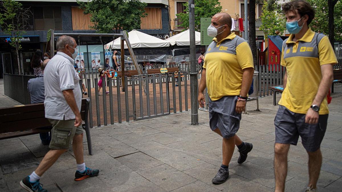 Dos agentes cívicos vigilan el cumplimiento de las medidas anticovid en la plaza Espanyola del barrio de la Torrassa, en L'Hospitalet, este martes 14 de julio