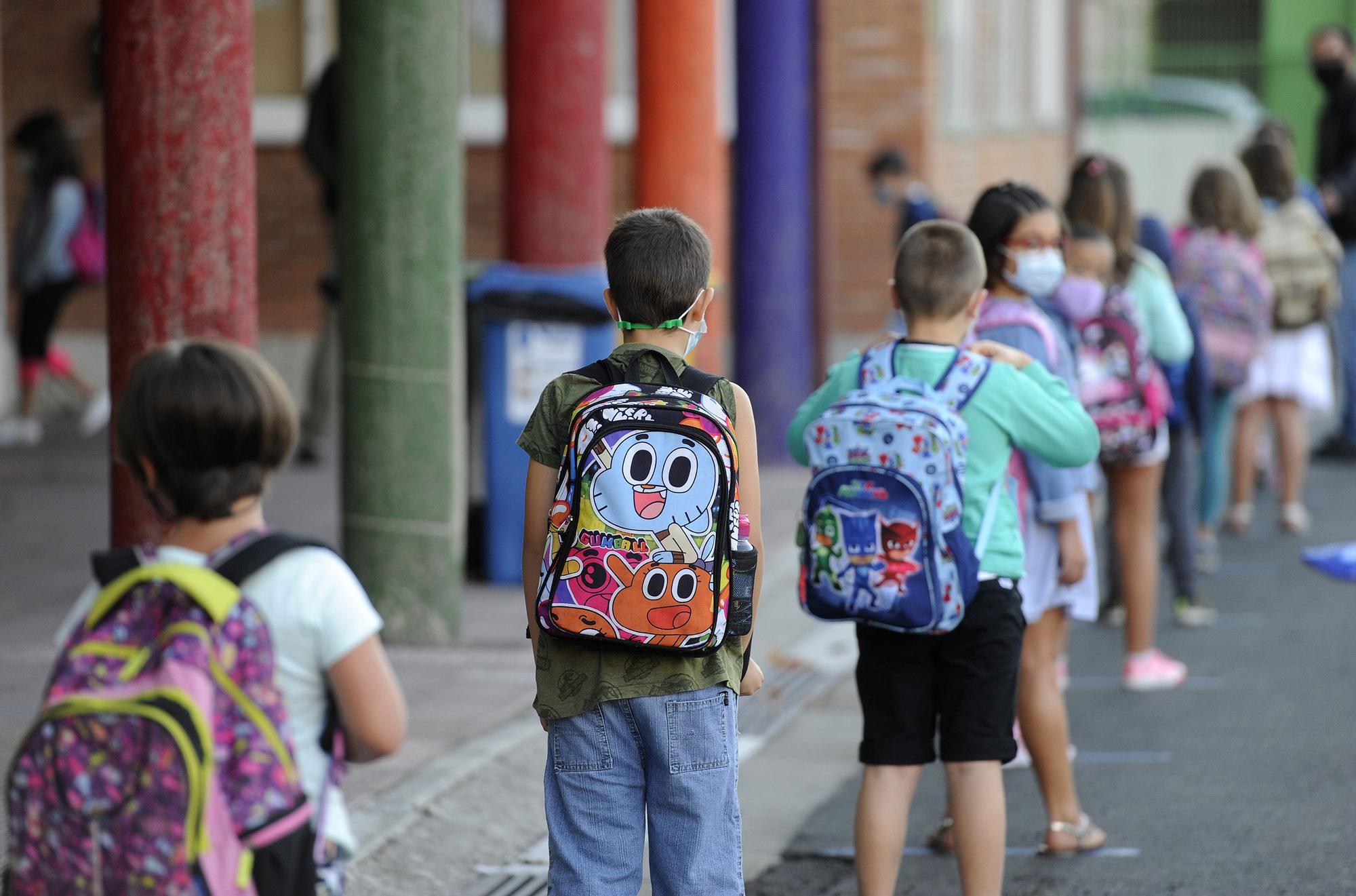 Niños en fila para entrar en un colegio con la mascarilla