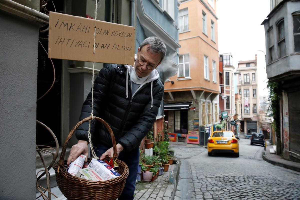 Jeffrey Tucker adds items to a basket he lowered from his window as a sign of social solidarity with poor and homeless people in need amid the  coronavirus disease (COVID-19) outbreak in Istanbul, Turkey April 3, 2020. Cardboard reads, Those who have the means, add. Those who need, take REUTERS/Umit Bektas