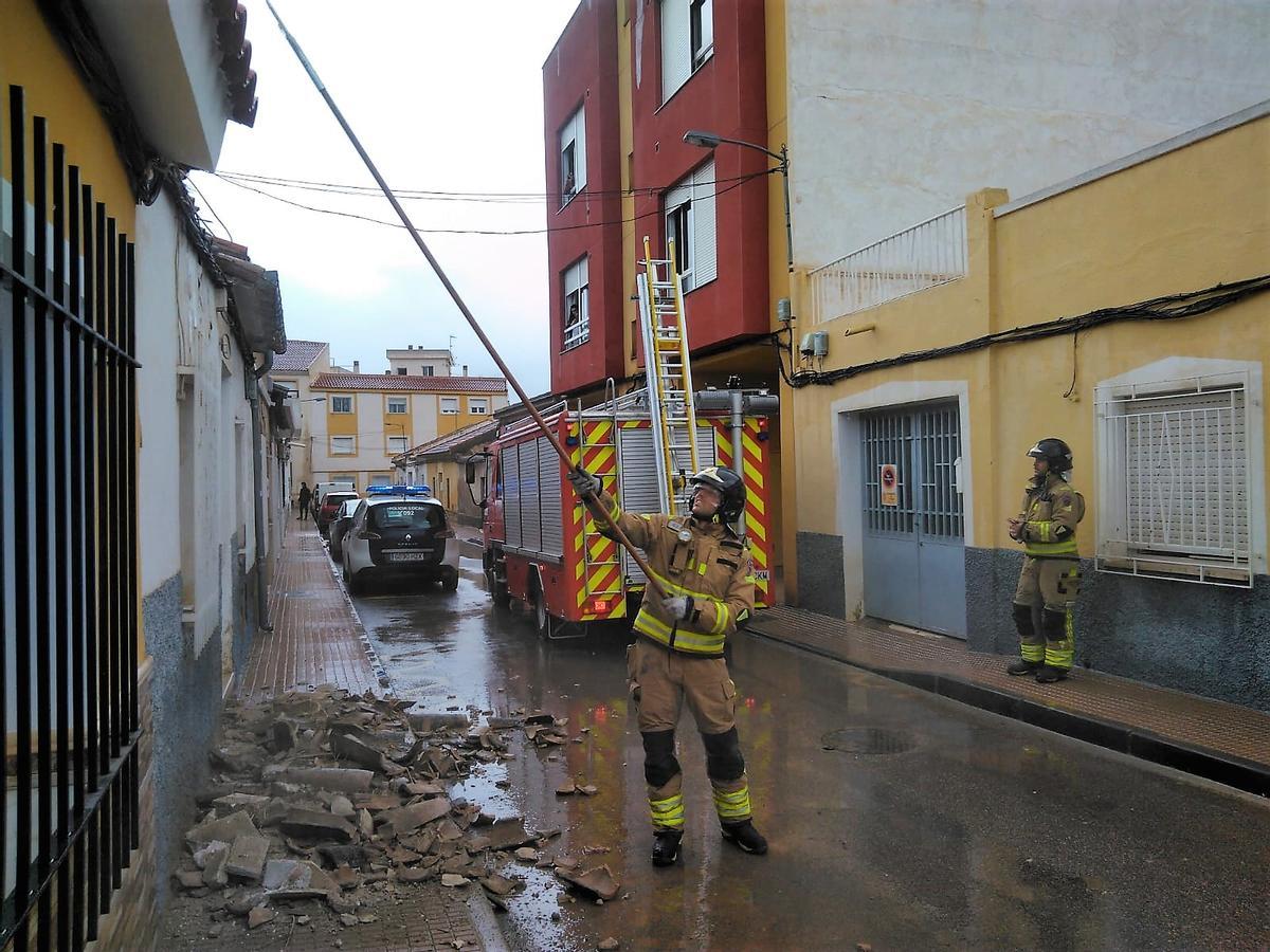 Bomberos trabajan en la vivienda de Totana de la que cayeron las tejas.
