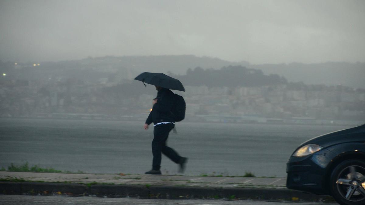 Una persona camina ayer por la tarde por el centro de Cangas durante un chaparrón.