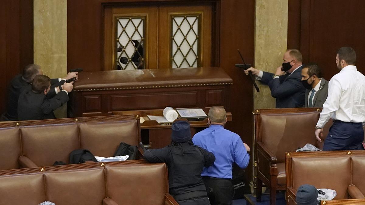 Policías del Capitolio apuntan a la puerta de la sala tras la irrupción de los manifestantes pro-Trump en el Congreso estadounidense