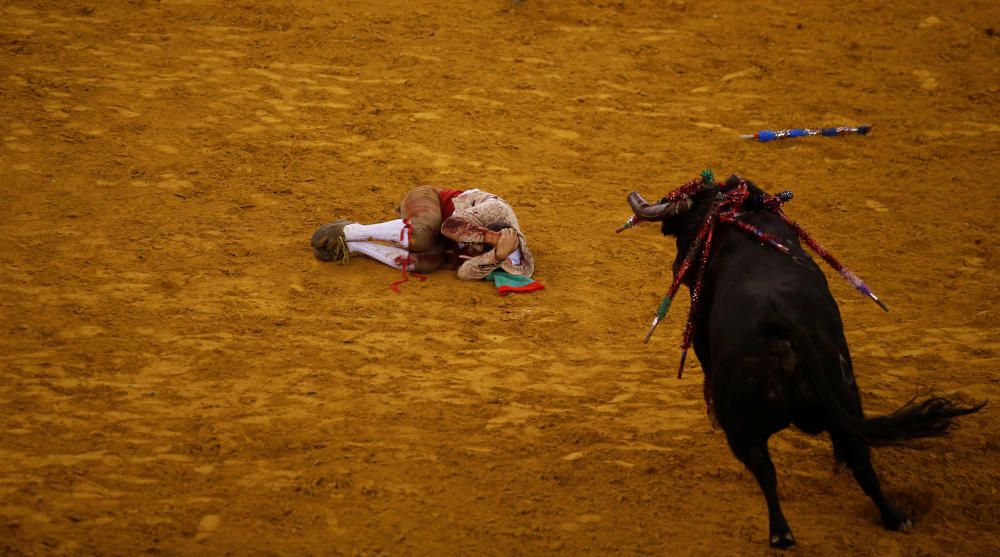 Un toro se dirige hacia un recortador que se protege en el suelo en la plaza de toros de Lisboa.