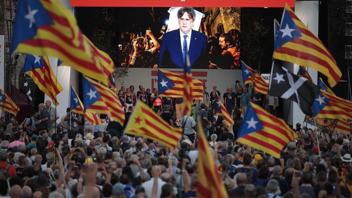 Manifestantes presencian el discurso del expresidente de la Generalitat, Carles Puigdemont, este domingo.