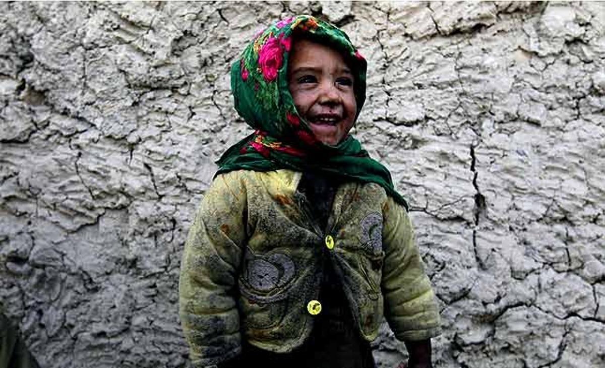 Una nena somriu davant de casa seva, a Kabul (Afganistan).