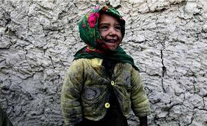 Una nena somriu davant de casa seva, a Kabul (Afganistan).