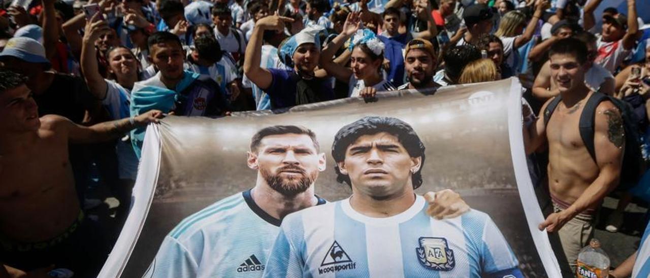 Aficionados argentinos sostienen una pancarta con las imágenes de Messi y Maradona. /