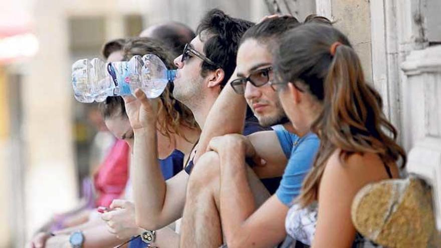 Unos jóvenes se refrescan para combatir el calor en la plaza de Cort.