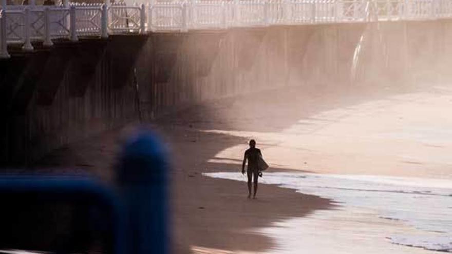 Un surfero se pasea por la orilla de la playa de Salinas.