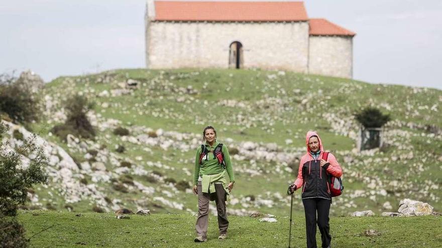 Dos senderistas, en la cima del Monsacro, con la capilla de la Magdalena al fondo.