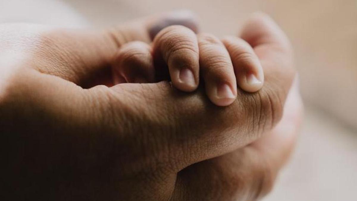 Un progenitor sostiene la mano de un pequeño.