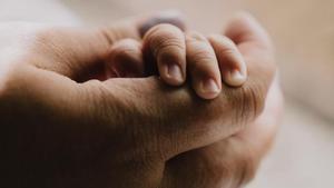 Un progenitor sostiene la mano de un pequeño.