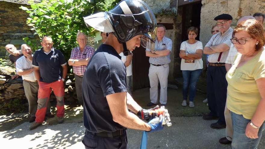 Manuel Rodríguez muestra a los vecinos cómo armar la manguera antes de su uso, en Fonteta.