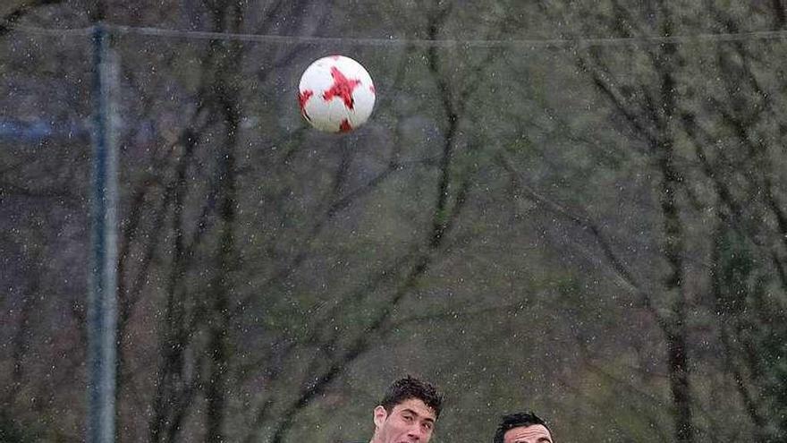 Asier, a la izquierda, disputa un balón aéreo con Chicho Villanueva, con Lobato de espaldas.