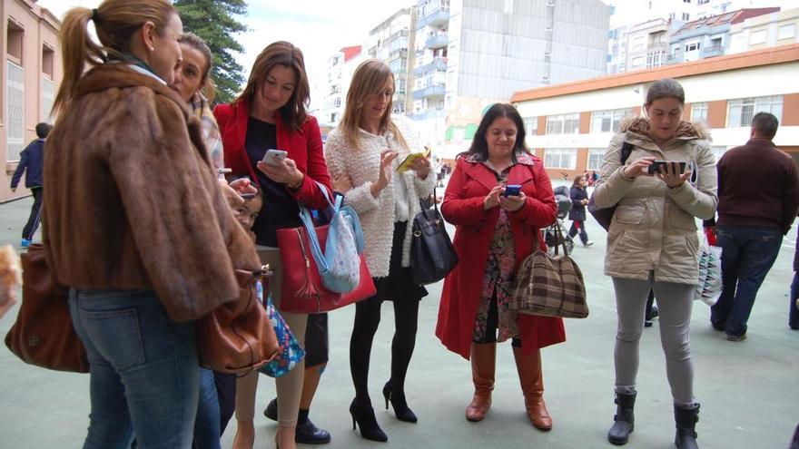 Padres consultan sus móviles en la entrada de un colegio de Vigo // A. Pinacho