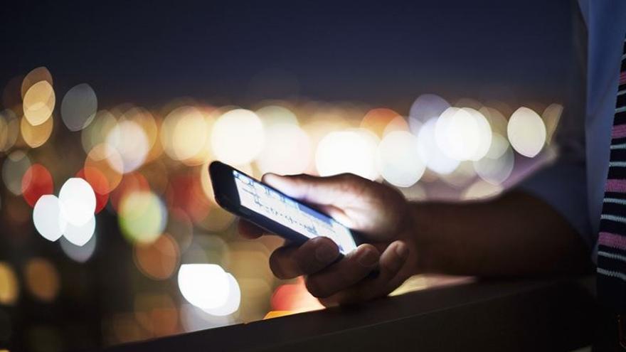 Archivo - Una persona utilizando su teléfono móvil (smartphone) por la noche