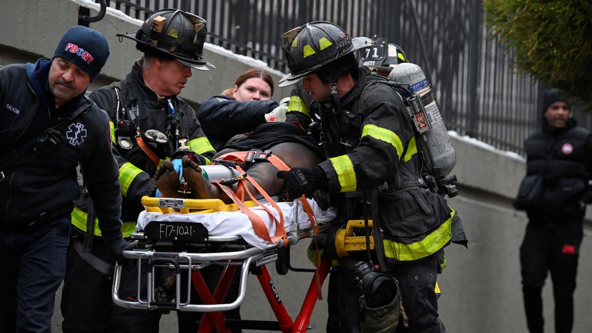 Bomberos atienden a un herido del edificio incendiado en el Bronx