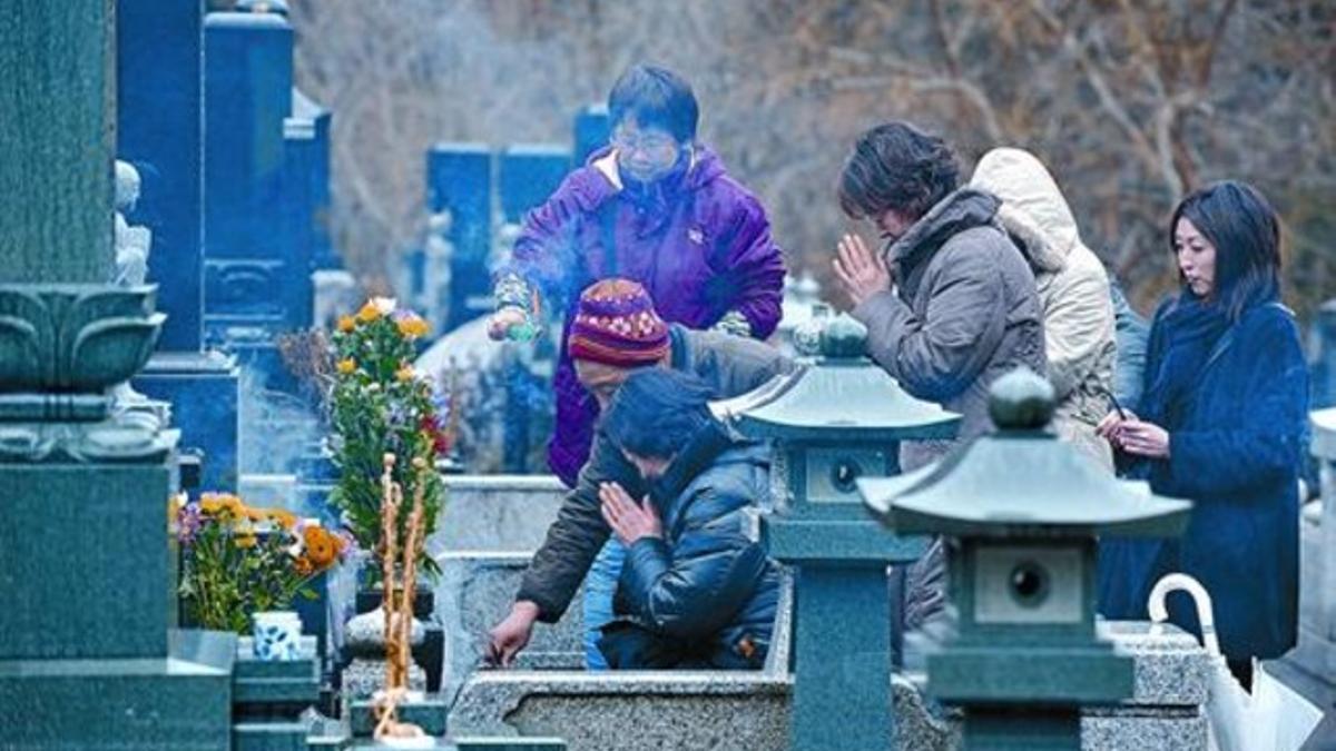Unos japoneses rezan junto a la tumba de un amigo fallecido en el terremoto de hace un año, en la localidad de Minamisanriku, ayer.