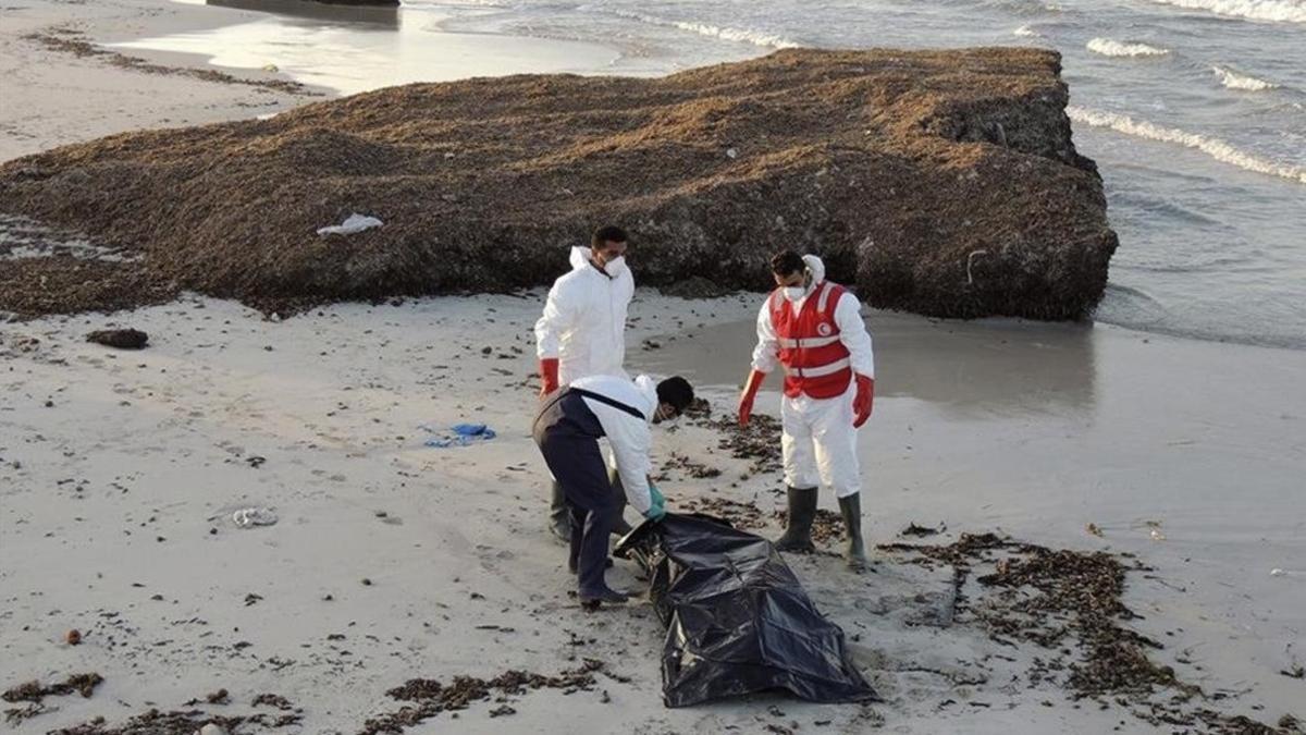 Miembros de la Media Luna Roja libia retiran el cadáver de un inmigrante fallecido en su intento de llegar a territorio europeo.