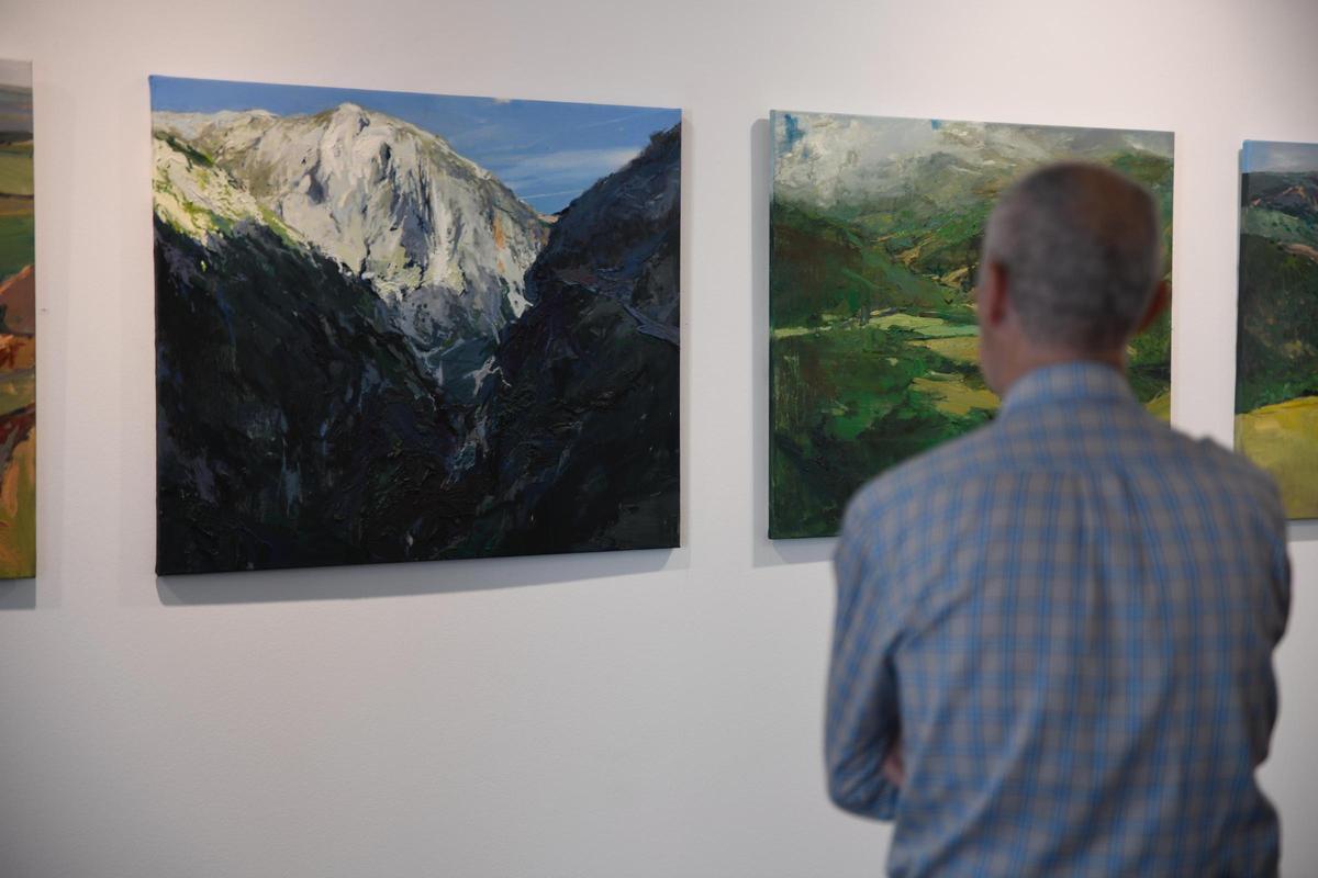 Un hombre contempla varios del cuadros exhibidos.