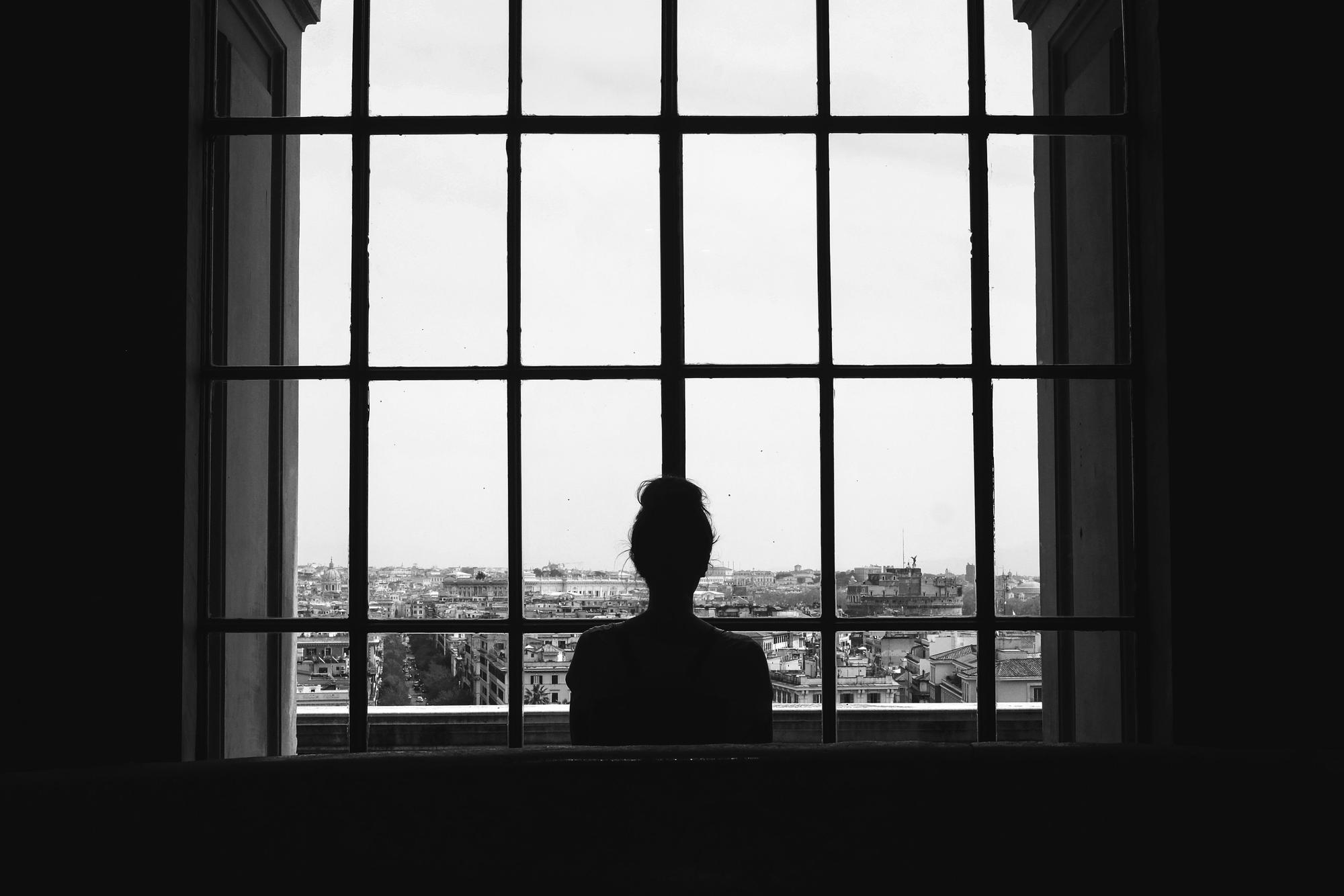 Una mujer frente a una ventana.