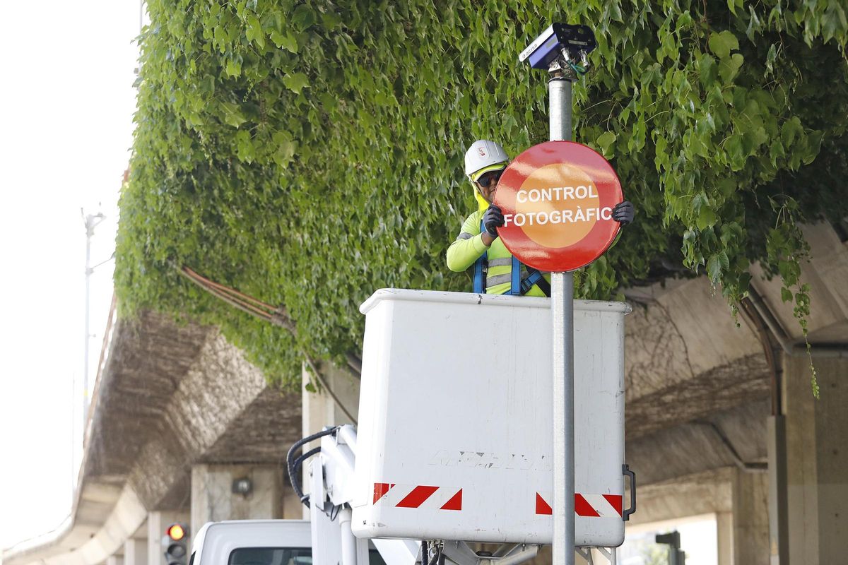 Un operari col·locant la senyalització de la càmera a la cruïlla entre el passeig d'Olot i el carrer Gironella.