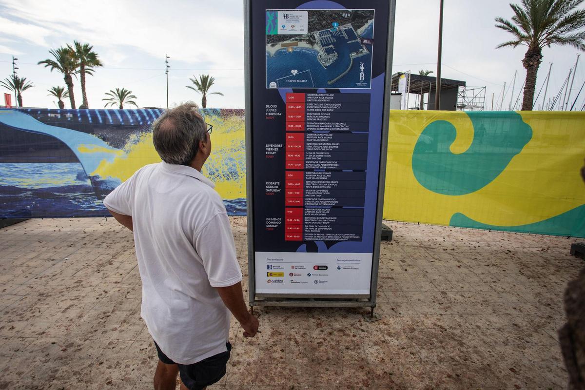 Un transeúnte mira el cartel con el programa de los actos de la regata preliminar de la Copa América de vela de Vilanova i la Geltrú, que se celebra entre el 14 y el 17 de septiembre..