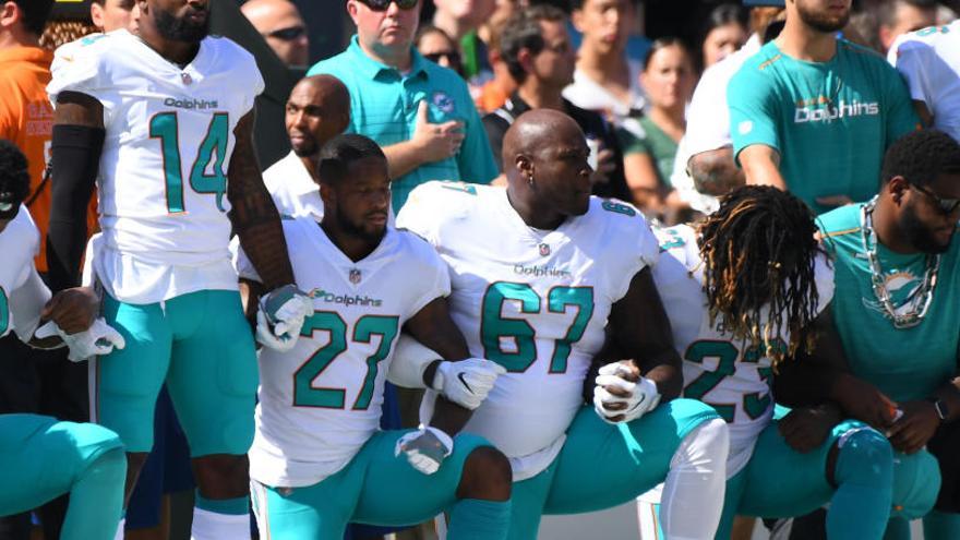 Jugadores de los Dolphins protestan de rodillas durante el himno.