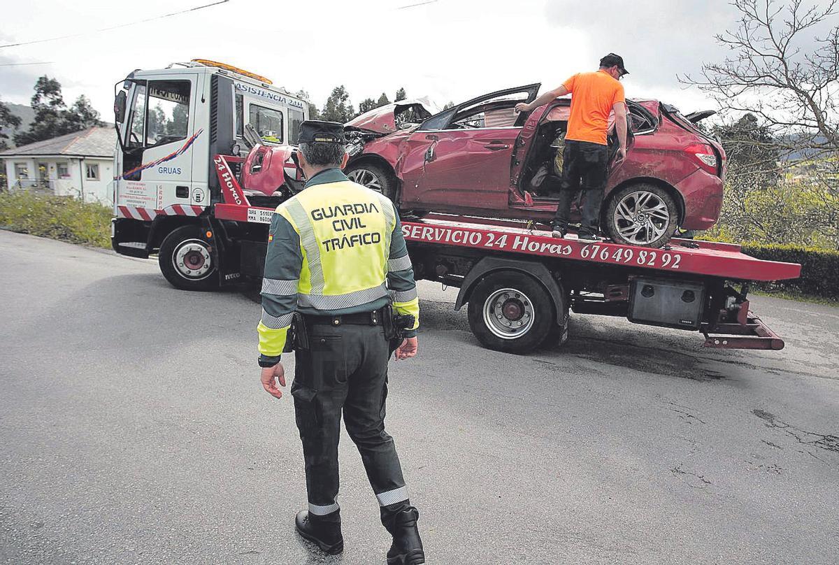 Un guardia civil vigila la retirada de un coche siniestrado por parte de una grúa en una carretera de Lugo.
