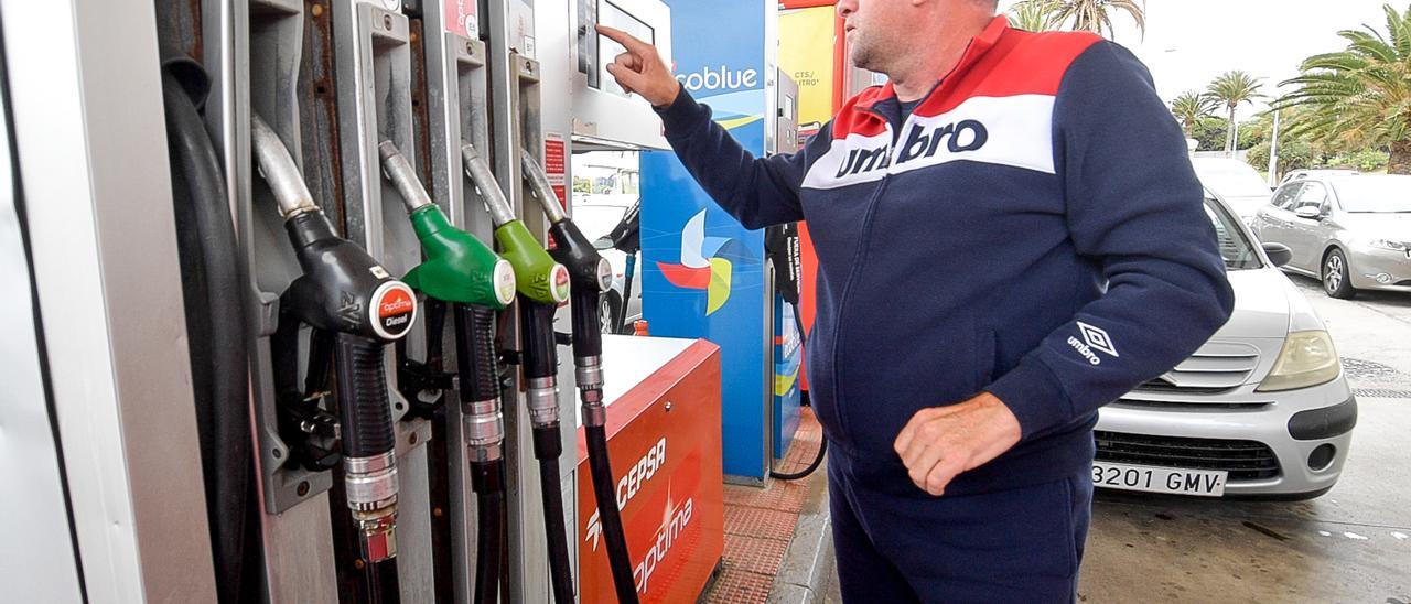 Un conductor junto a un surtidor en una gasolinera.