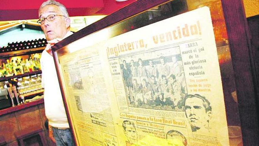 Monchu Hevia sostiene el cuadro que contiene la portada del 3 de julio de 1950 publicada por el diario «Marca», en el restaurante Casa Baizán. / ángel gonzález