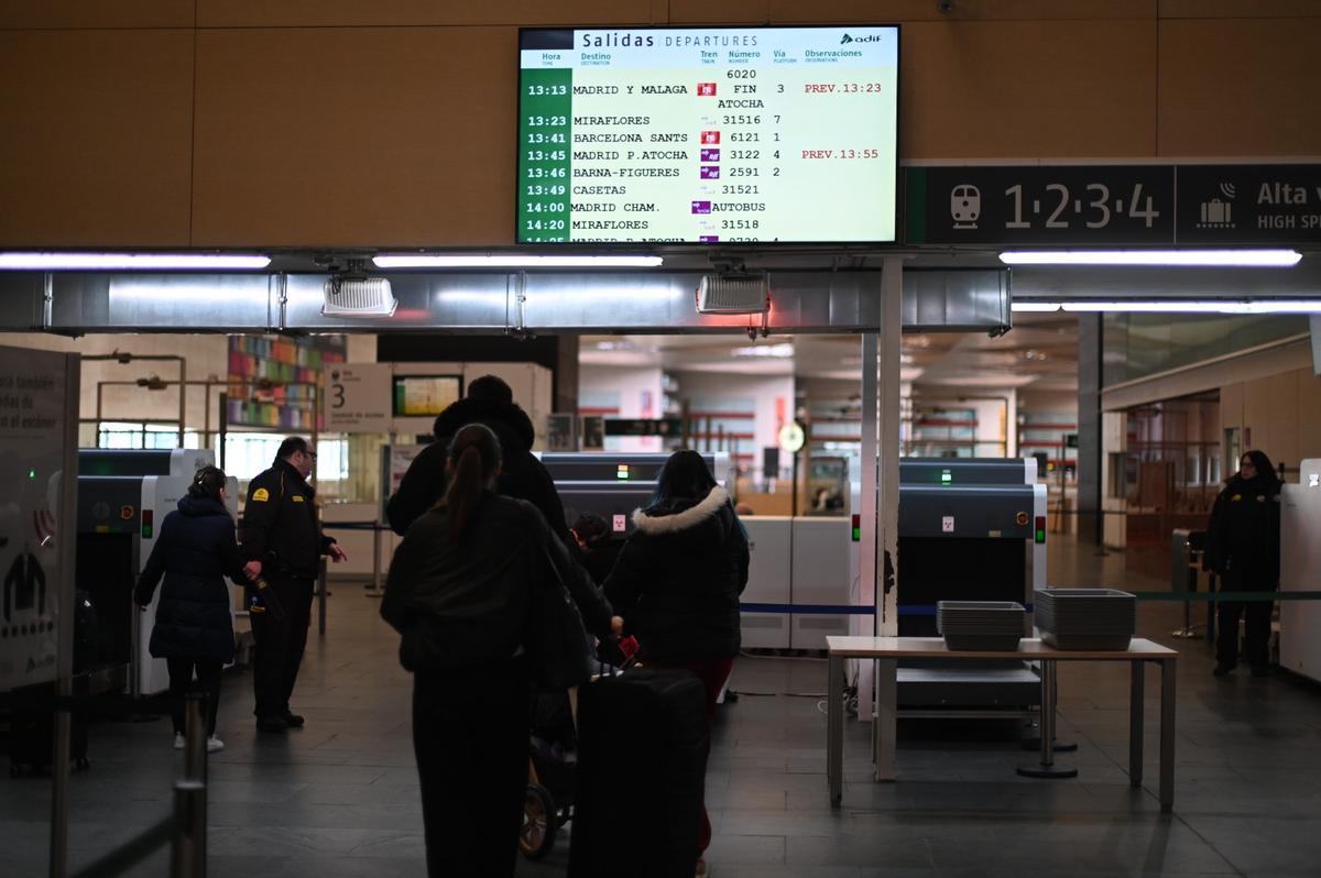 Viajeros en la estación de Delicias de Zaragoza ante el panel que anuncia los retrasos ferroviarios.