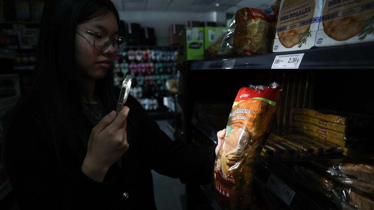 Una joven compra en una tienda a oscuras en València.