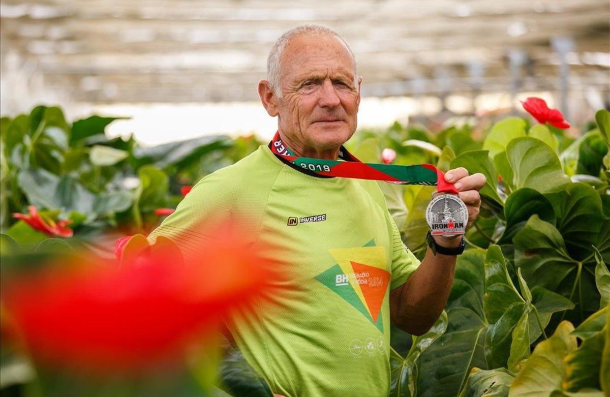 Toni Noé muestra la medalla del Ironman rodeado de flores.