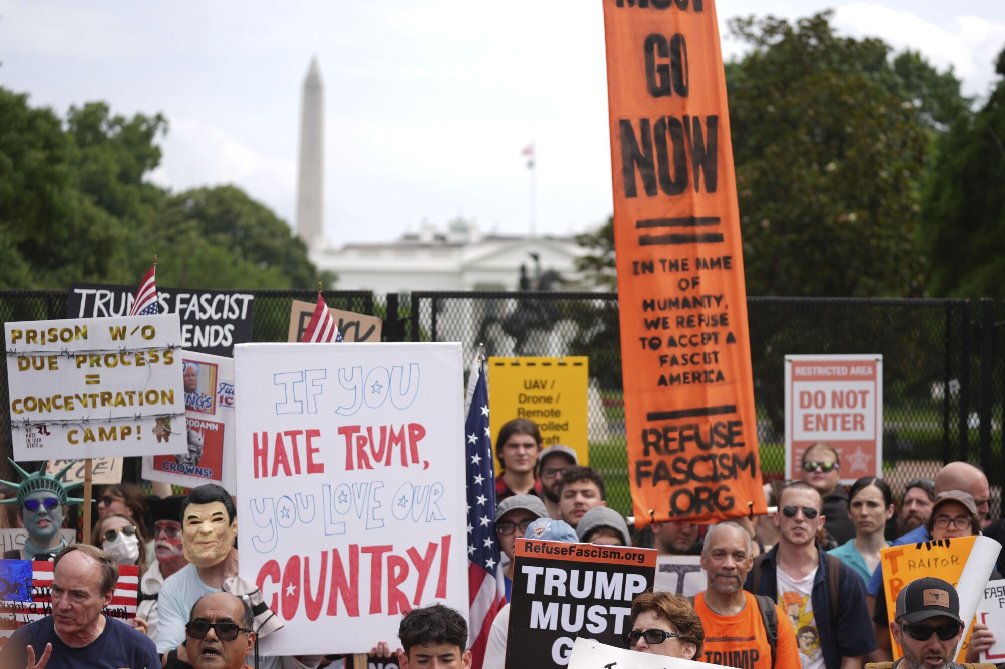 Demonstrators stand near the White House during a protest taking place on the day of a military parade commemorating the Army's 250th anniversary, coinciding with President Donald Trump's 79th birthday, Saturday, June 14, 2025, in Washington. (AP Photo/Evan Vucci)