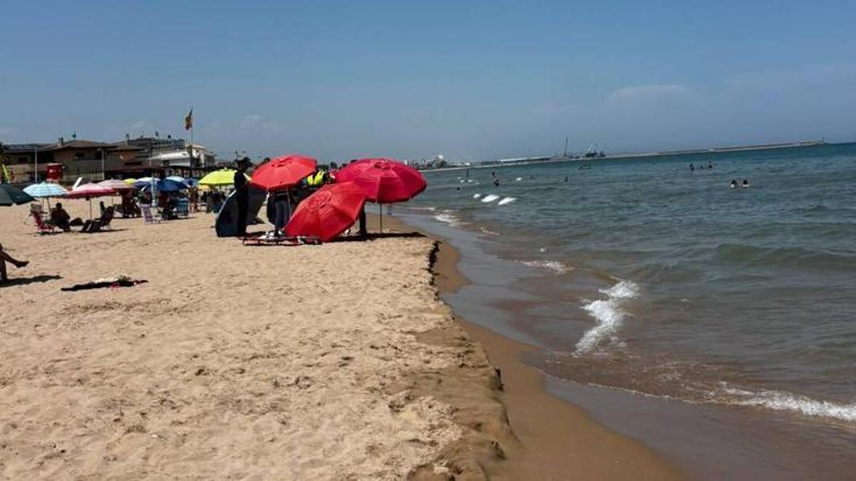 El fallecido, bajo las sobrillas cedidas por los bañistas en la playa de Daimús