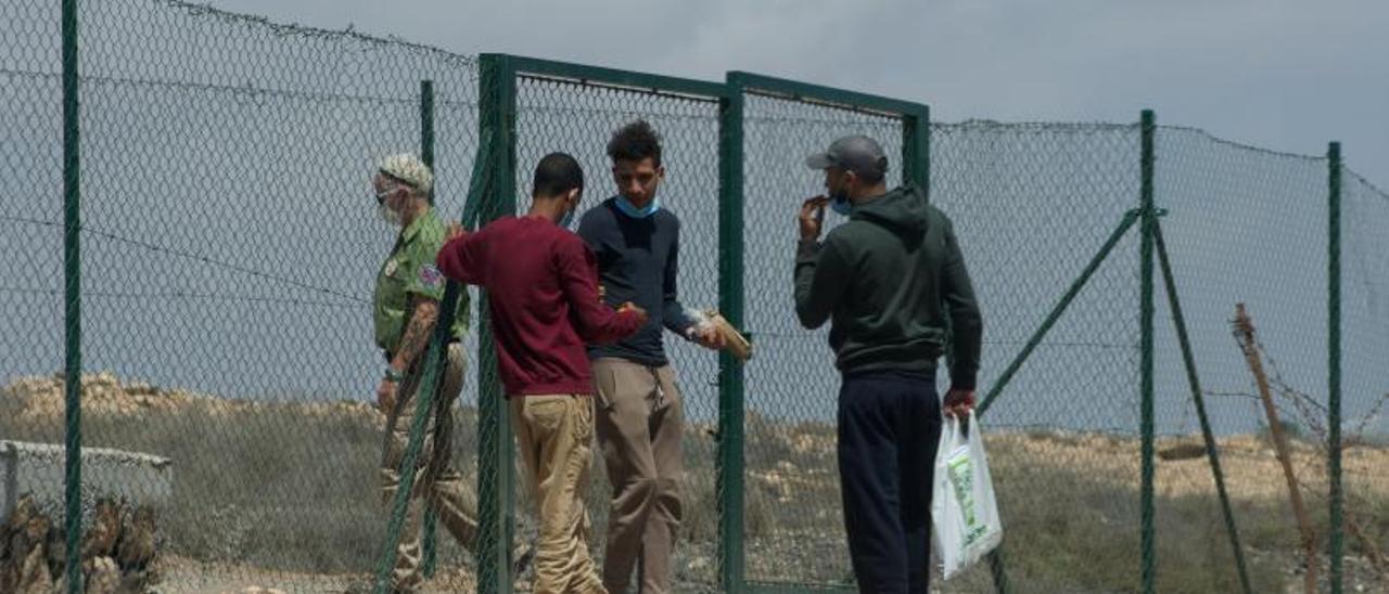 Un grupo de inmigrantes, en el exterior del campamento de El Matorral, en Fuerteventura, donde se ha detectado un enfermo por coronavirus. | | EFE