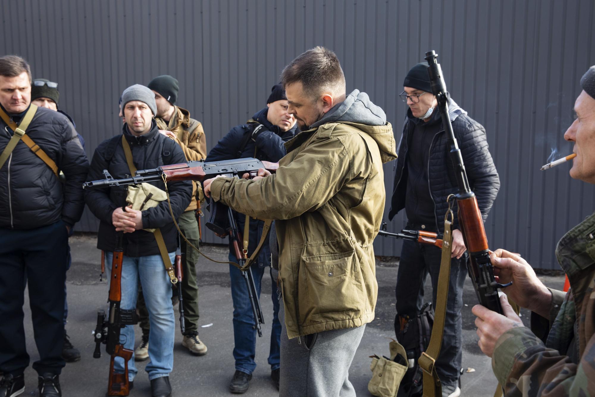 Un grupo de hombres recibe armas y munición en Kiev, 25 de febrero de 2022.