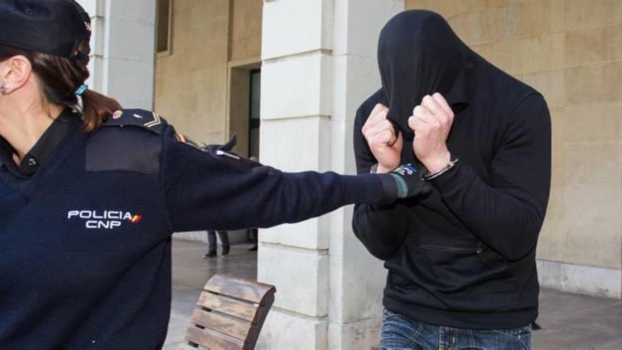 Una policía nacional traslada ayer al acusado tras concluir el juicio en la Audiencia de Alicante.