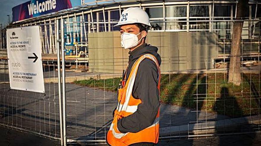 Un trabajador con mascarilla junto al pabellón en el que se iba a celebrar el Mobile World Congress.